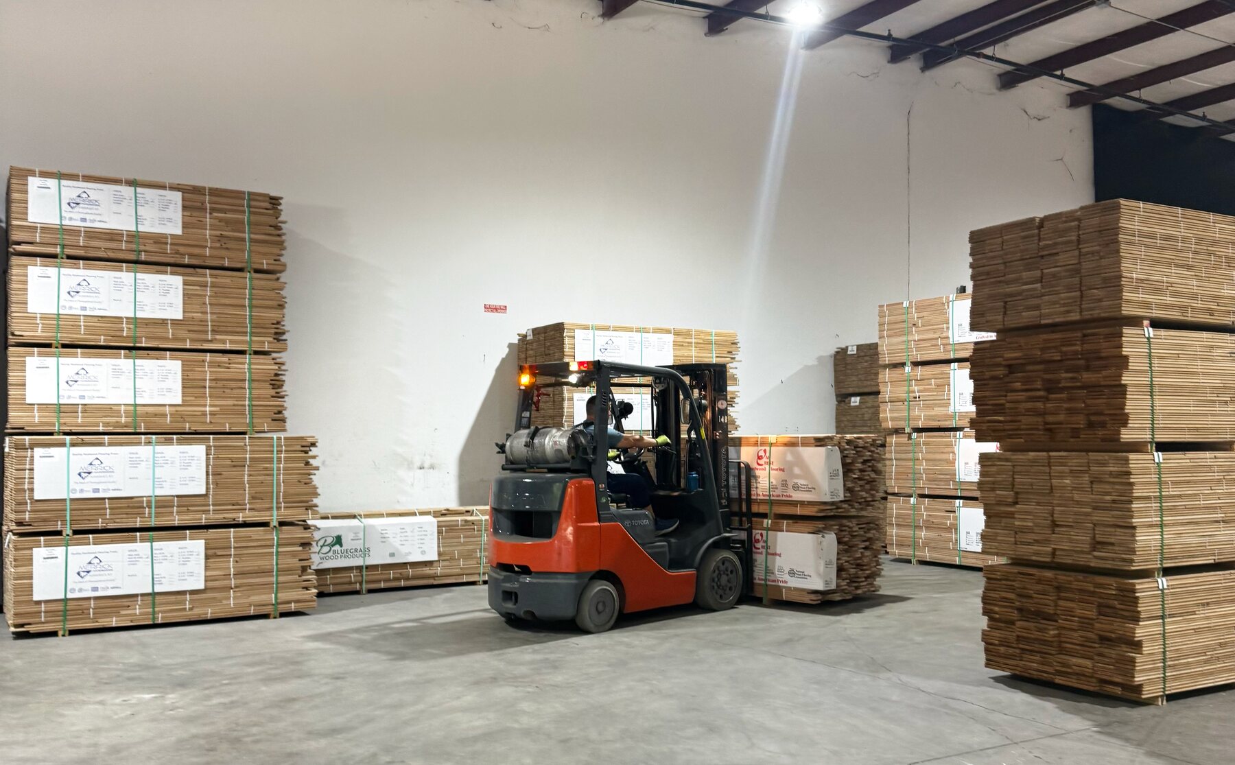 NDM Floors warehouse — pallets of hardwood flooring loaded by forklift